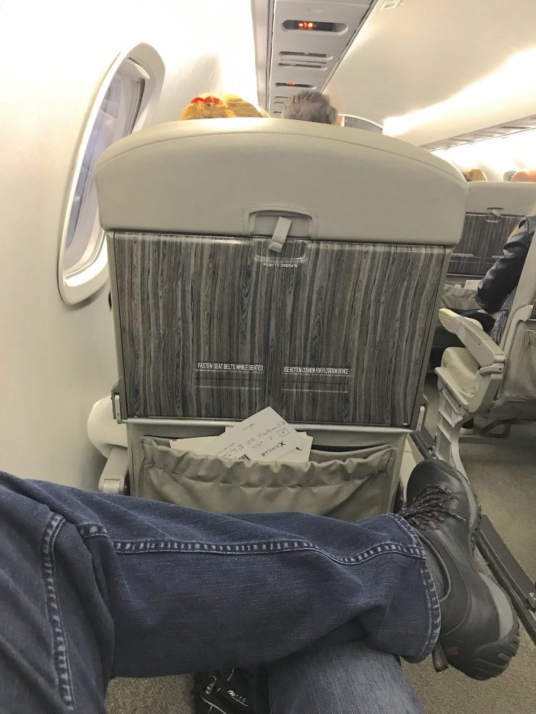 Picture of male crossing his legs in the exit row of a jet