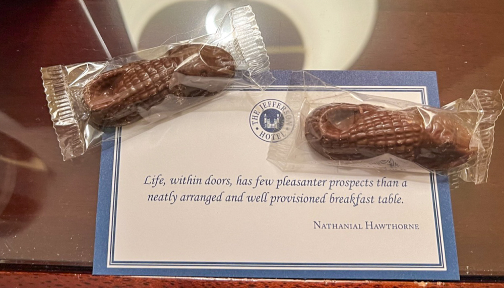 Postcard with a quote from Nathanial Hawthorne. Two small chocolates in the shape of an alligator are sitting on the left and right side of the postcard.